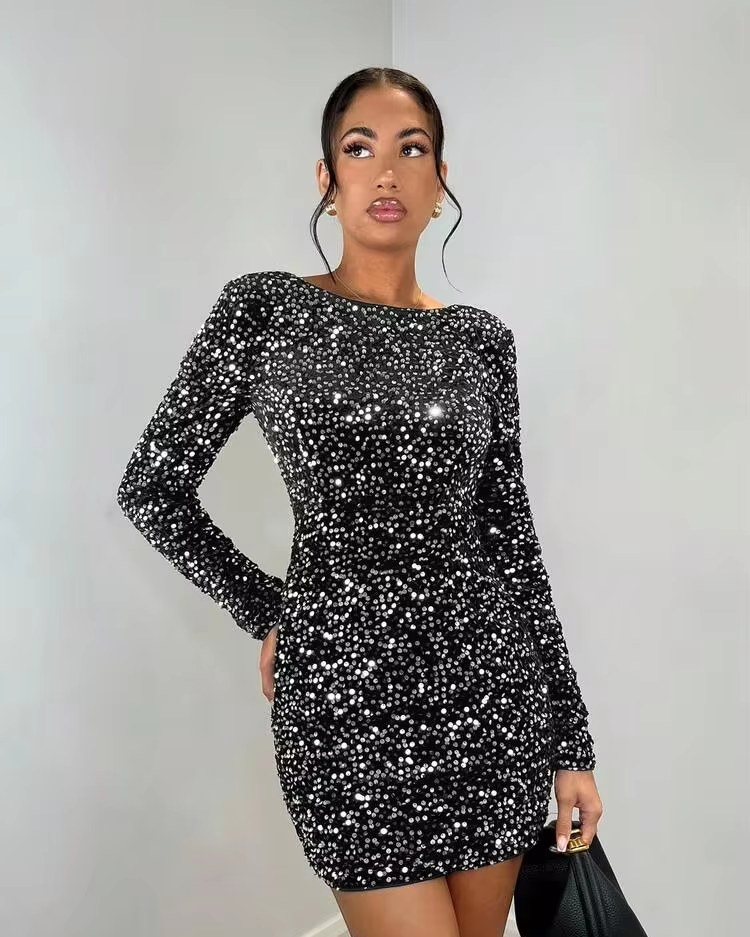 woman in a long sleeve black velvet sequin mini dress holding a small black bag