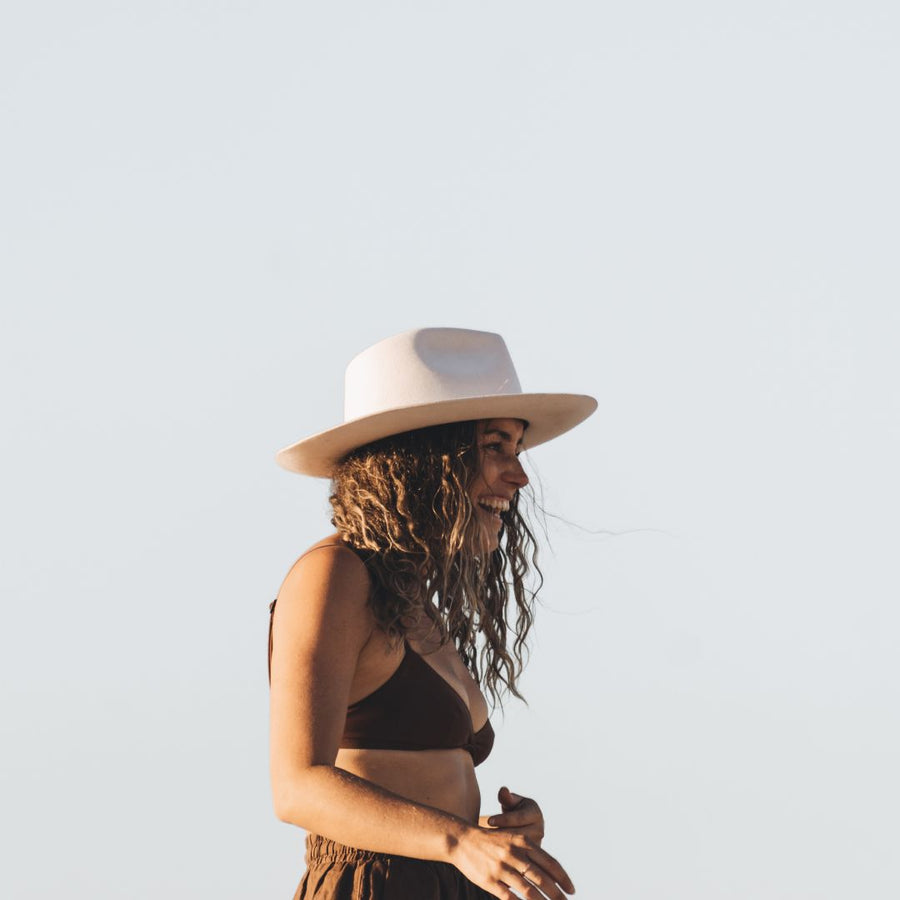 woman in a white upturned fedora and brown bikini top outdoors